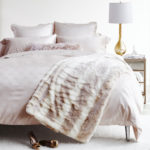 wide shot of faux fur throw on creamy white bedroom