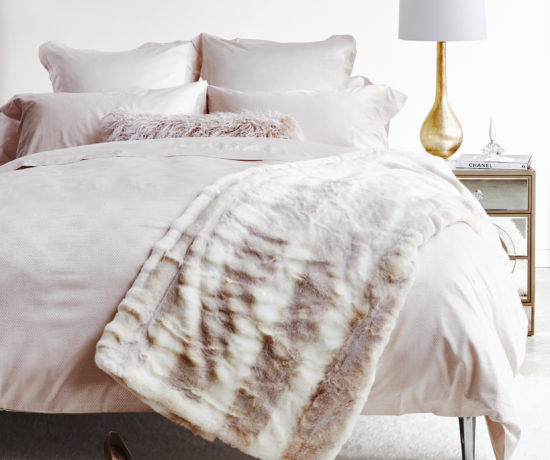 wide shot of faux fur throw on creamy white bedroom