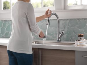 Esque touch faucet in kitchen setting with grey backsplash