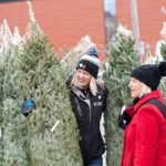 two women butying a real christmas tree from local sellers