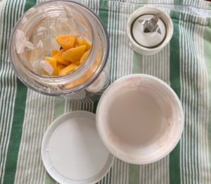 Tip for saving money and food waste wih smoothie blender, yogurt and frozen fruit on green striped tablecloth