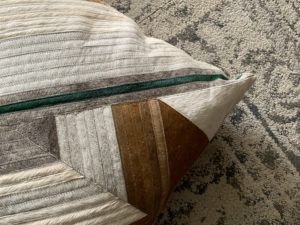 GRey hide pillow on graphic carpet tile floor.