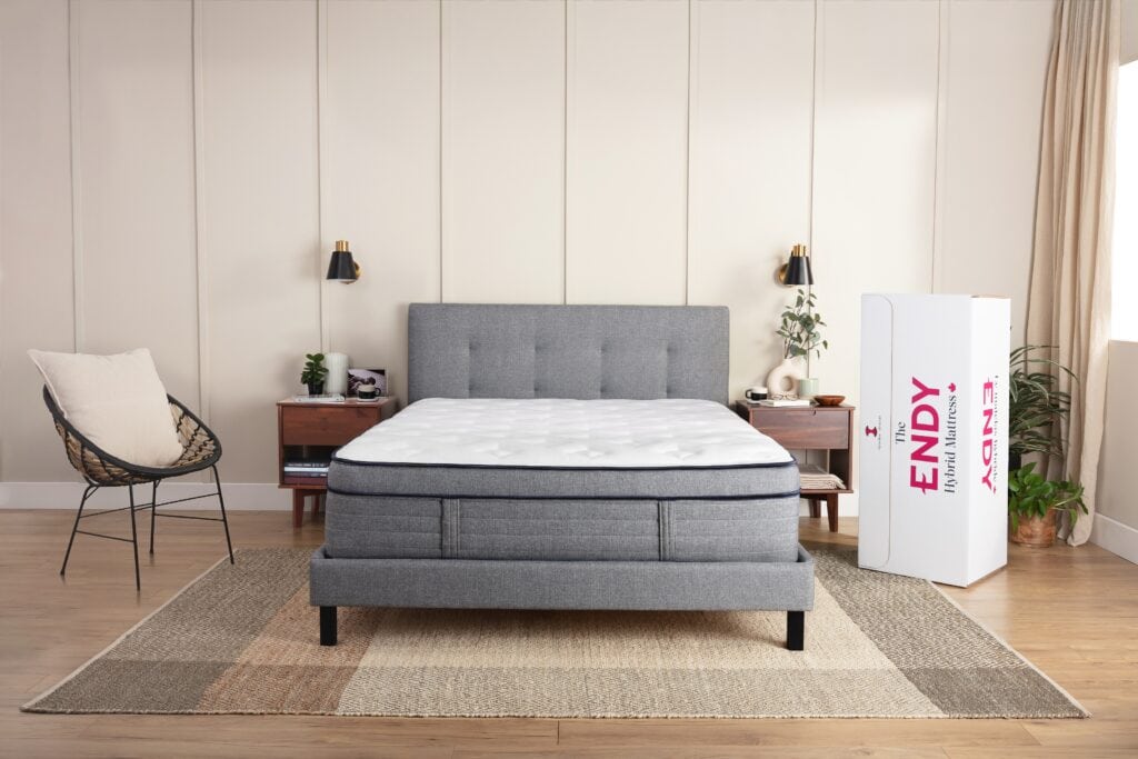 An Endy mattress in a box opened in a bedroom with grey blue decor ready for the vacuum