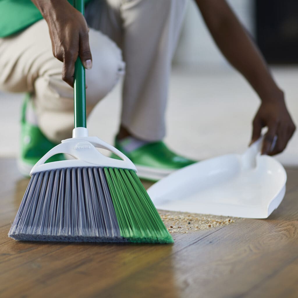 A person uses a broom and pan that will get a wash and a rinse as part of spring cleaning