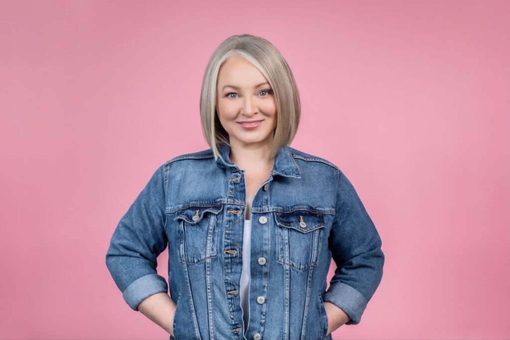 Paint expert Leigh Ann Allaire Perrault in a blue demin jacket against a hot pink background. 