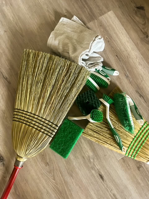 a selection of brooms, brushes, and scrubbers gathered for sustainable household cleaning