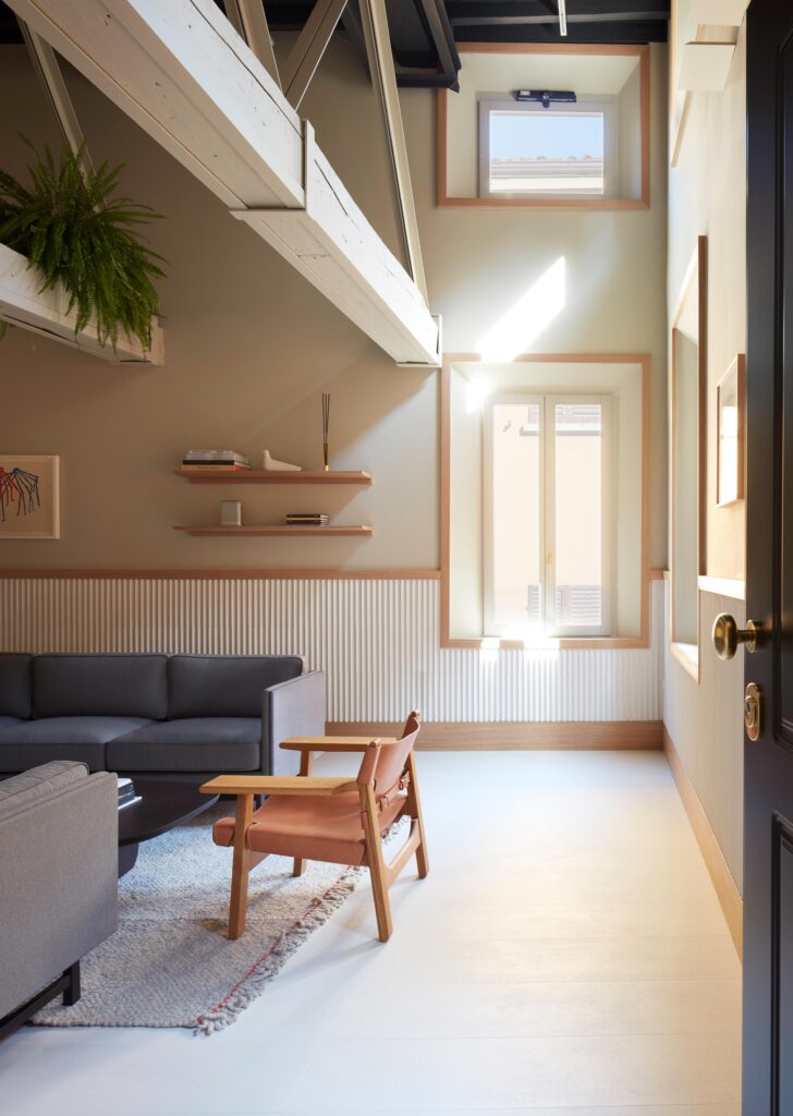 A large room with fluted stone wainscotting and large light wood trim that works with various cream and beige tones. Ceramic tiles from Mutina in Italy.